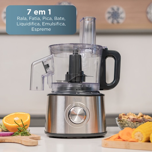 BLACK+DECKER food processor on a kitchen counter with fruits, nuts, and vegetables nearby.