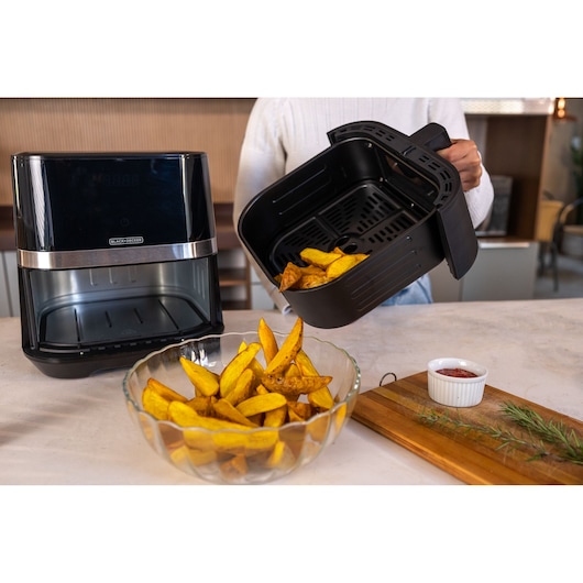 BLACK+DECKER AFDLG air fryer, black with chrome accent, kitchen setting with fries being served from basket.
