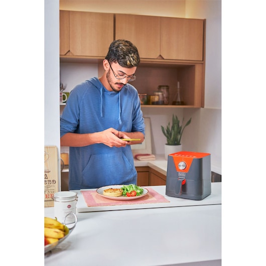 Photo of BLACKDECKER AFM2_1 air fryer in kitchen, next to a plate of food on a counter.