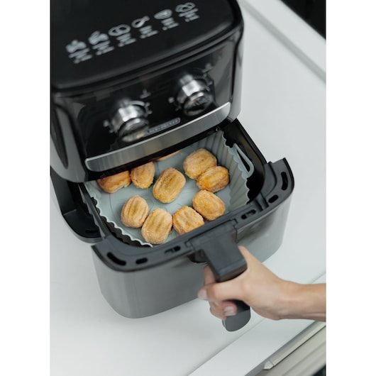 BLACKDECKER AFM4 air fryer with control knobs, basket drawer open showing food inside, top angle.