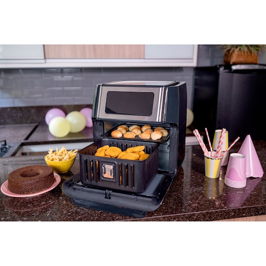 BLACKDECKER AFO12G air fryer in kitchen, filled with snacks and pastries, party items nearby.