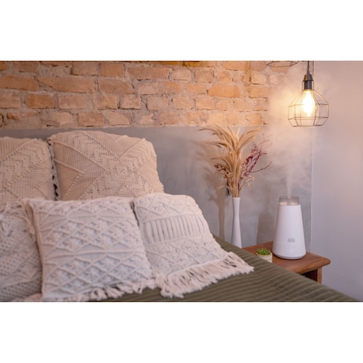 BLACKDECKER AIR2000N humidifier on wooden nightstand in cozy bedroom setting with textured pillows.