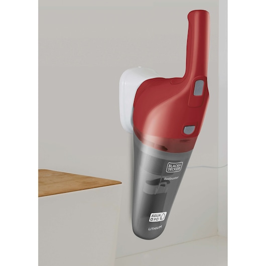 A BLACK+DECKER handheld vacuum cleaner with a red and gray design is mounted on a wall charging station. The vacuum is labeled for both wet and dry use and features lithium battery technology.