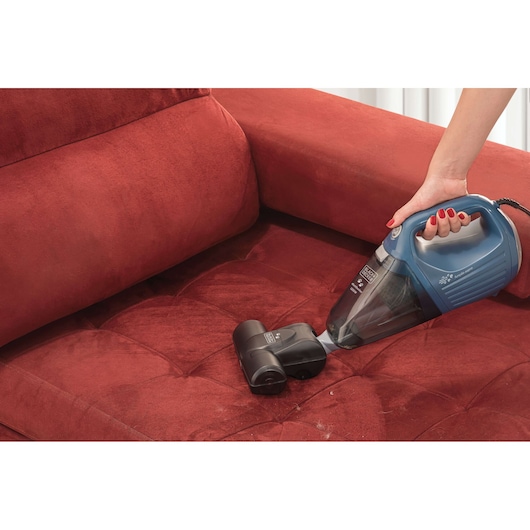BLACKDECKER APS1200PET handheld vacuum cleaner cleaning a red sofa upholstery.