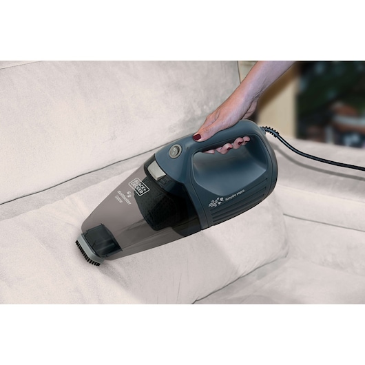 Photo of BLACK+DECKER APS1200PET handheld vacuum cleaner being used to clean a light-colored sofa.