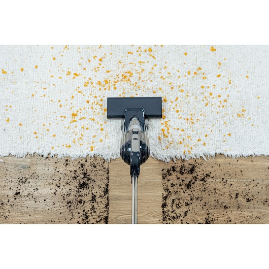 BLACKDECKER AV15 vacuum cleaner top view on rug and wood floor cleaning scattered debris.
