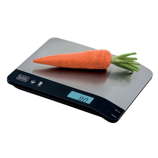 BLACK+DECKER BC500 digital kitchen scale with stainless steel surface and carrot on top, angled view.