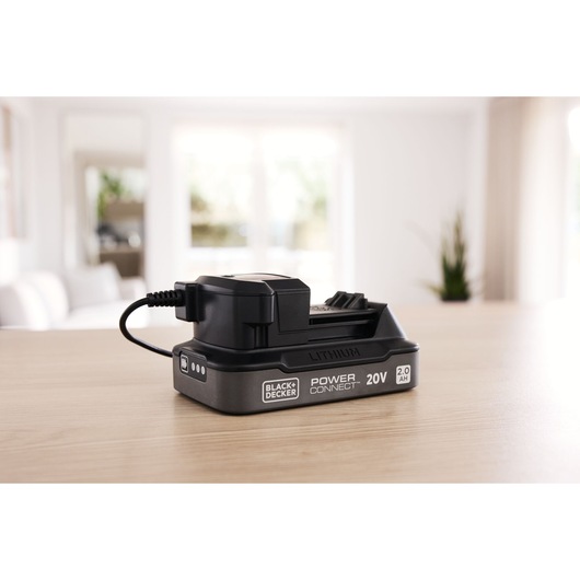 Photo of BLACK+DECKER 20V lithium Power Connect battery charger BDL2020S on a wooden table, indoor setting.
