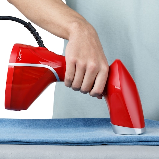 Photo of BLACKDECKER BDV2100 red handheld garment steamer in use over blue fabric.