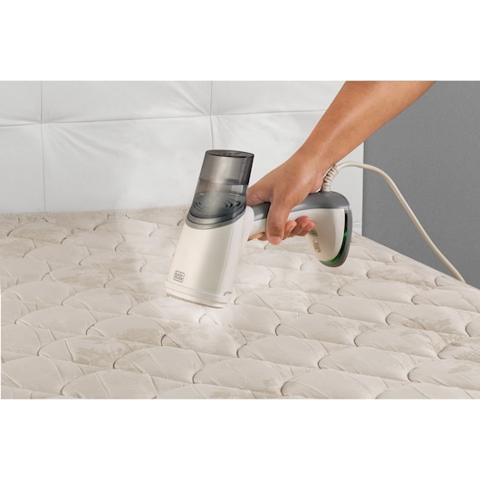 BLACKDECKER BDV3000 handheld vacuum cleaner on mattress, close-up angle.