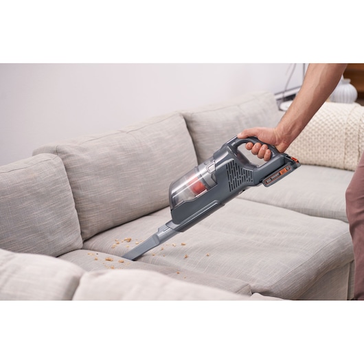 Photo of BLACKDECKER BHFEA18D1 handheld vacuum cleaning crumbs from a beige sofa.