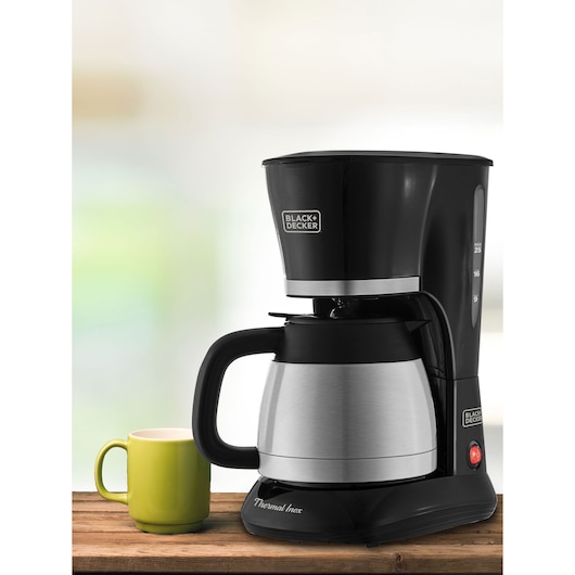 BLACKDECKER CM200I coffee maker with stainless steel thermal carafe, side angle, next to green mug on wood.