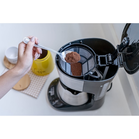 Photo of BLACKDECKER CM250P coffee maker with a spoon of ground coffee being added to the filter from a top angle.