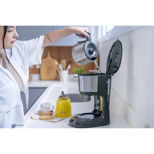 Photo of BLACKDECKER CM250P coffee maker on kitchen counter with person pouring water into reservoir.