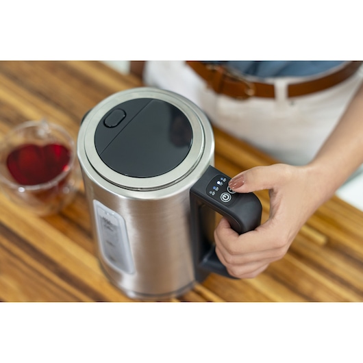 Programmable Electric Kettle. Hand holds kettle handle. Aerial view