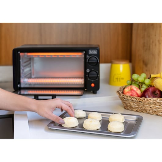 BLACKDECKER FT9N toaster oven on a kitchen counter with a tray of dough balls and a fruit basket nearby.