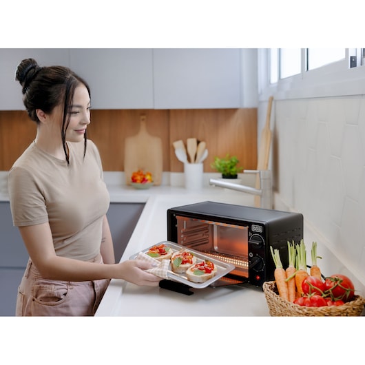 Photo of BLACKDECKER FT9N toaster oven on kitchen counter with tray of bruschetta and basket of vegetables nearby.