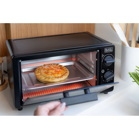 A BLACK+DECKER toaster oven with a pie heating inside, positioned on a kitchen counter.