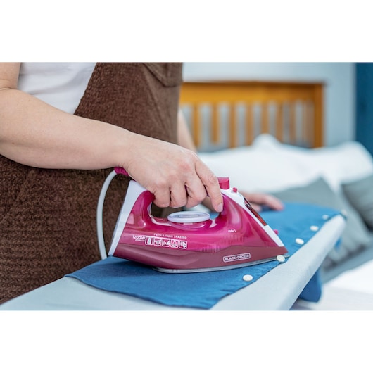 BLACKDECKER FX2250 steam iron in use on blue shirt, side angle view.
