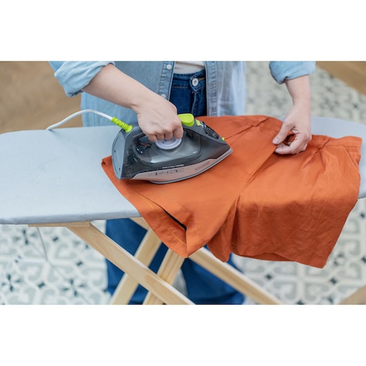 Photo of BLACKDECKER FX2750 steam iron in use on orange fabric on ironing board.