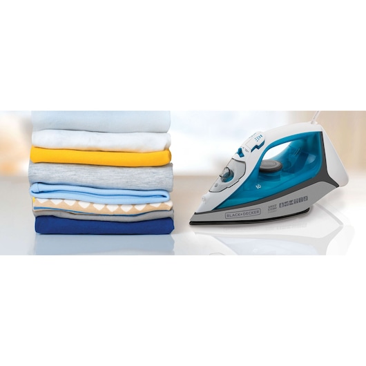 A BLACK+DECKER steam iron placed next to a neatly folded stack of colorful clothes on a white surface.