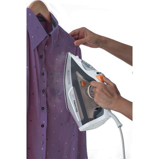 Photo of BLACKDECKER FX3100 steam iron in use, steaming a purple shirt with small patterns on a hanger.