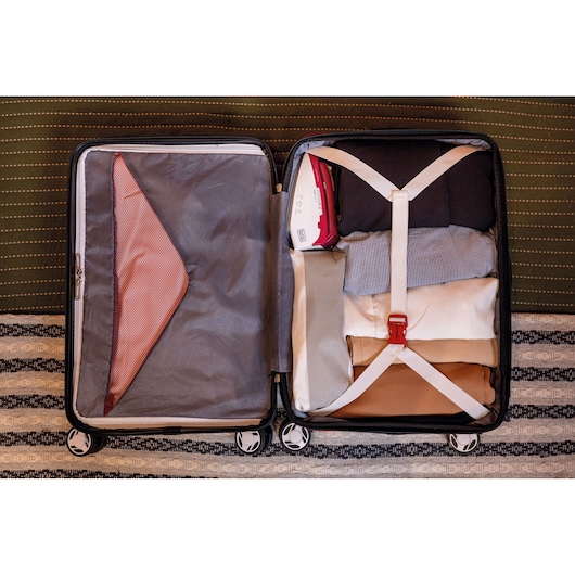 BLACKDECKER FXVG1 handheld iron packed in suitcase with folded clothes, top view, travel organization.