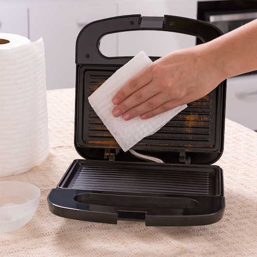 BLACKDECKER GS800 sandwich maker being cleaned with a paper towel in a kitchen.