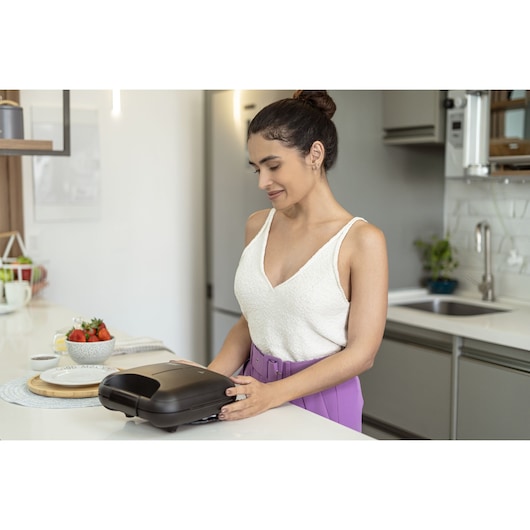Photo of BLACKDECKER GW750 sandwich maker on kitchen counter with person in white top and purple pants.