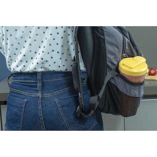 BLACKDECKER LP320 blender bottle with yellow lid in grey backpack side pocket, photo from behind at waist height.