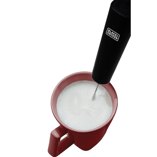 BLACK+DECKER M150 handheld milk frother in use foaming milk in a red mug, top-down angle, white background.