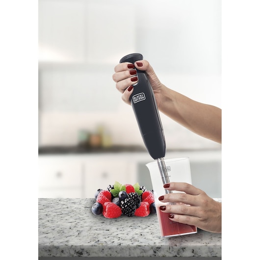 BLACKDECKER M300 hand blender in use blending red liquid in clear cup, assorted berries on counter.