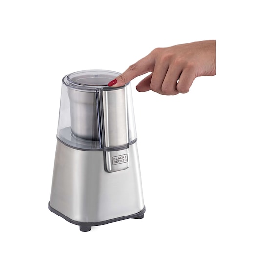 BLACKDECKER MG200 stainless steel coffee grinder with clear lid, shown side view, hand pressing top button.