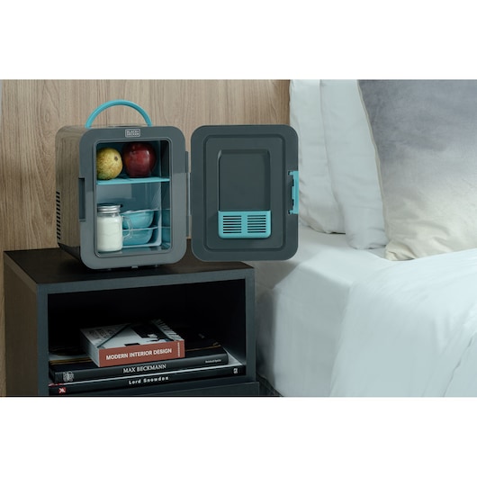 BLACKDECKER MR60 compact mini fridge with open door, showing milk jar and fruits, on bedside table.
