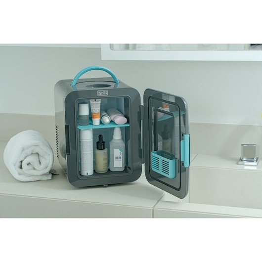 BLACKDECKER MR60 mini fridge with blue handle open on bathroom counter with skincare products inside.