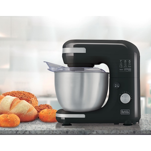 BLACKDECKER PLAN2000P black stand mixer with stainless steel bowl on kitchen counter beside assorted bread.