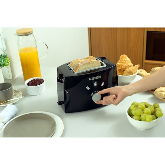 Photo of BLACK+DECKER TO810 black toaster with bread slices, breakfast setting with juice, jam, and pastries.